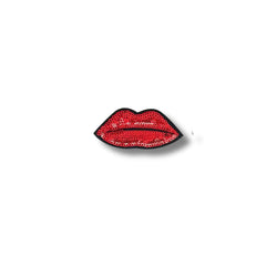 Fotografía de un parche bordado con forma de labios rojos brillantes decorados con lentejuelas, sobre fondo blanco.