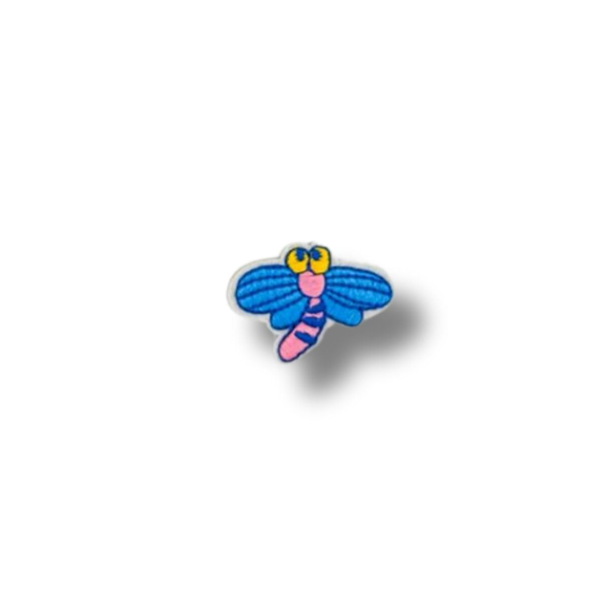 Parche bordado de libélula azul con cuerpo rosado y ojos amarillos, estilo caricaturesco sobre fondo blanco.