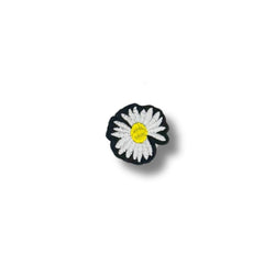 Parche con margarita de pétalos blancos y centro amarillo intenso, contorno negro que resalta el diseño.