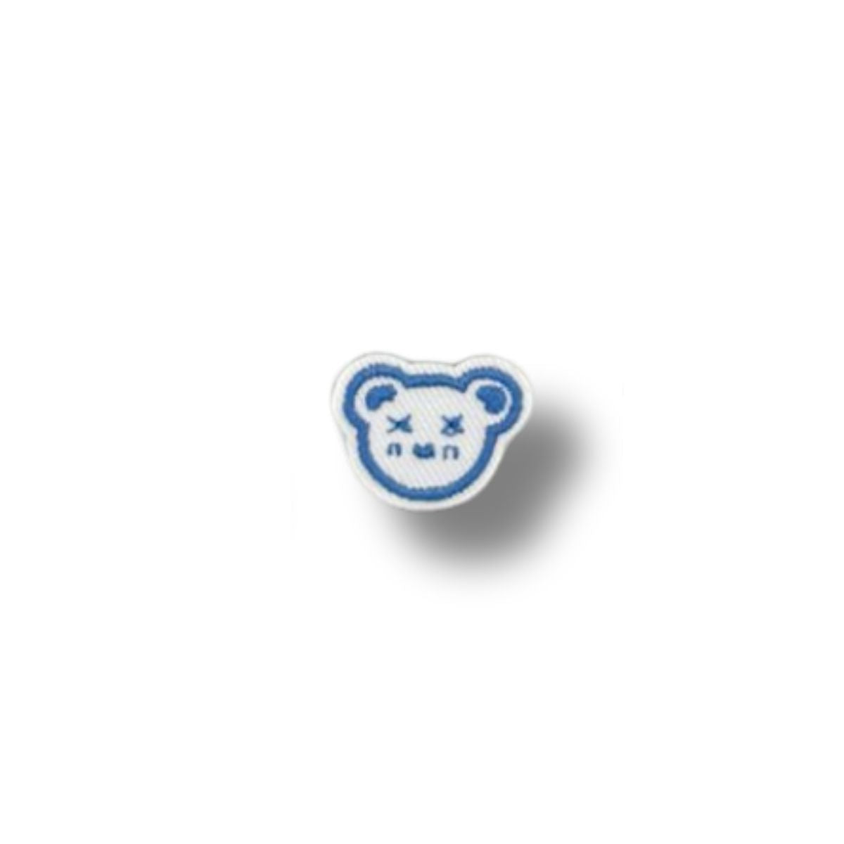 Parche bordado de pequeño oso azul con ojos en forma de “X” y expresión soñolienta.