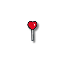 Imagen de un parche bordado con diseño de paleta en forma de corazón rojo brillante, con contorno negro y fondo blanco limpio, ideal para prendas juveniles.